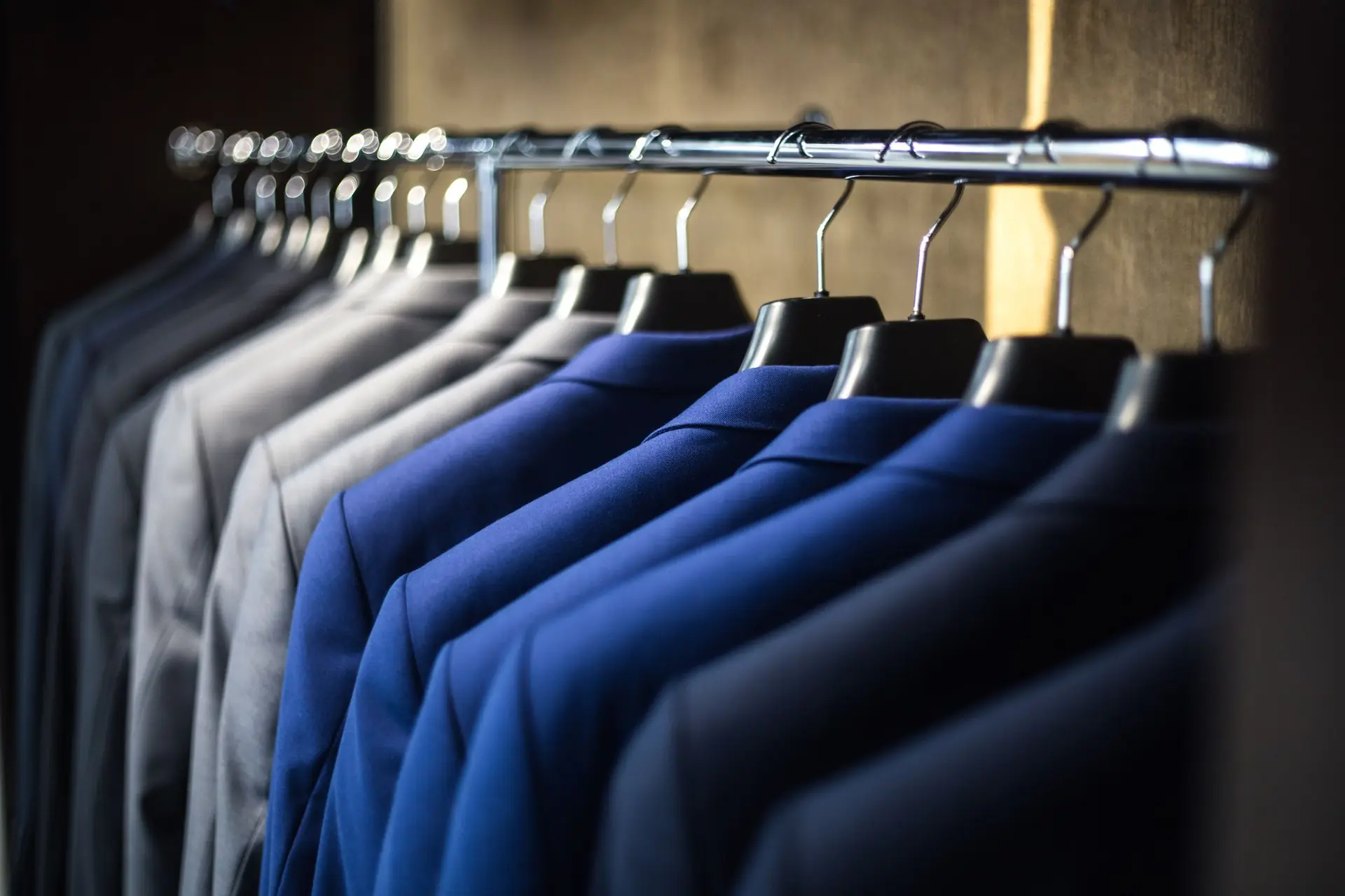 Navy suit jackets hanging on a tailor’s rail